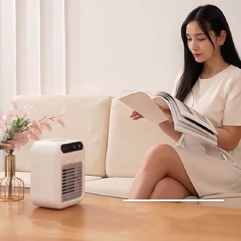 A woman reading a magazine next to a Homís AirCooler Pro in a cozy living room setting.